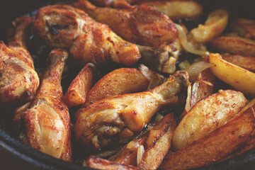 fried chicken drumsticks with potato slices, in a clay pan, baked in the oven, with spices, homemade, no people,
