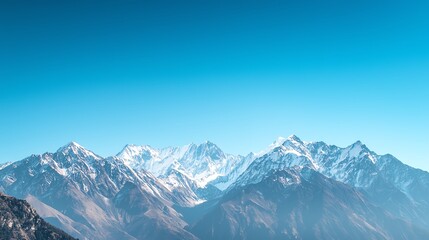 Fototapeta premium Breathtaking view of snow-capped mountains under a clear blue sky, perfect for nature and adventure enthusiasts.
