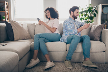 Photo of two positive people girl guy sit couch use cell device in flat room indoors