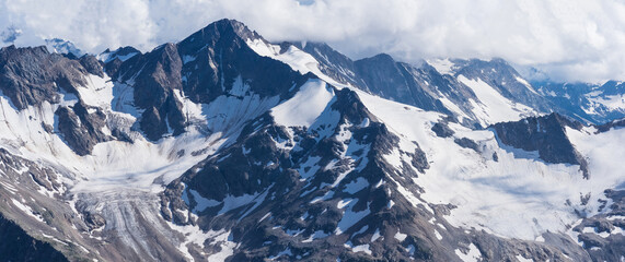 Naklejka premium panoramic highlands landscape, peaks and glaciers among clouds