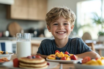 A young boy with a joyful expression sits at a kitchen table, surrounded by plates of fresh fruits and pancakes, ready to enjoy a healthy breakfast