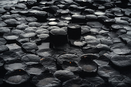 Der Giant&rsquo;s Causeway Detailaufnahme der gleichm&auml;&szlig;ig sechseckigen Querschnitt geformten schwarzen nassen Basalts&auml;ulen in Nordirland