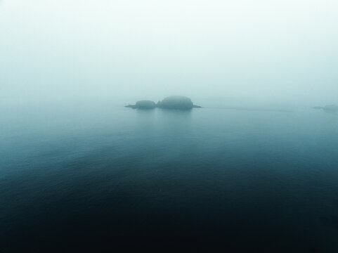 Einsame Insel im Meer umgeben von mystischen regnerischen Nebel von Nordirland Sheep Island