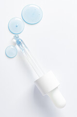 Drops of cosmetic serum and a pipette. A skin care product. White background. Copy space.
