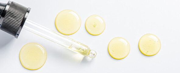 Drops of cosmetic serum and a pipette. A skin care product. White background.