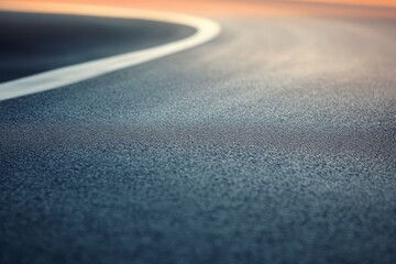 A clean asphalt road bends gracefully to the right, illuminated by soft pastel colors in the fading light of dusk