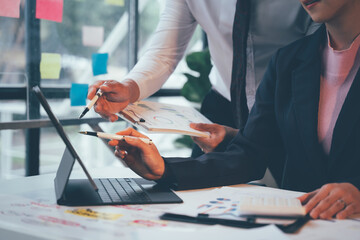 Strategic Collaboration in Action: Two business professionals analyze data on a tablet, fostering...