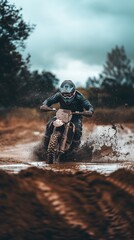 A dirt biker in full gear speeds through a muddy track, splashing water and mud during an off-road adventure.