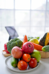 Plate overflowing with fresh vegetables and fruits is sitting on a table, promoting a healthy lifestyle