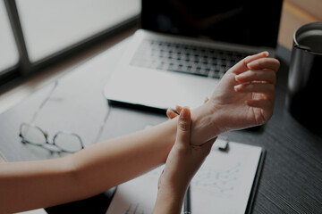 A tired business woman working for a long time and typing the computer, so her wrist is hurt and...