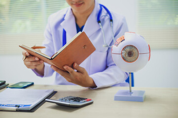 An ophthalmologist explains eye diseases using an eye model at an examination table in a hospital...