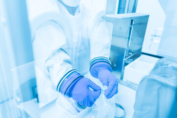 Close up scientist wearing blue gloves working with normal saline in the flume hood at...