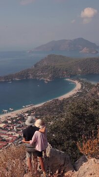 Man and woman hugging overlooking blue lagoon in Oludeniz, T&uuml;rkiye. View from the back.