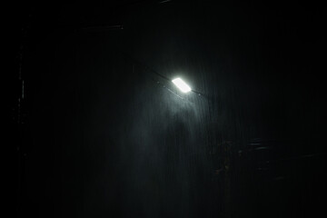 Falling raindrops on night background.Heavy rainy and wind with public street lights on black...