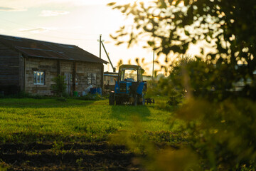 Blue tractor in the evening, at sunset after a hard day's work.A green field