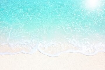 Serene beach scene with turquoise water gently lapping on soft white sand under a bright sun.