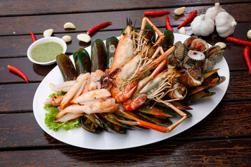 Seafood plate with shrimp shellfish crab squid cockle spotted babylon with seafood sauce chili lemon lime serve on dining table