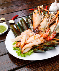 Seafood plate with shrimp shellfish crab squid cockle spotted babylon with seafood sauce chili lemon lime serve on dining table