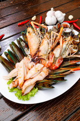 Seafood plate with shrimp shellfish crab squid cockle spotted babylon with seafood sauce chili lemon lime serve on dining table