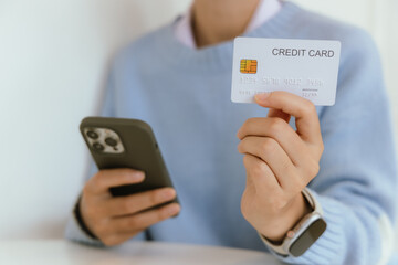 Woman at home making online payments on her laptop. She holds her credit card and enters the details on a secure e-commerce website, reflecting the convenience of online banking and shopping in the mo