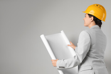 Engineer in hard hat with draft on grey background, space for text