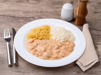 Shrimp strogonoff with rice and straw potato over wooden table