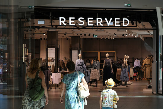 Gdansk, Poland - 14 August 2024: Boutique with clothes of Reserved brand in shopping mall Forum Gdansk. Family with child enter store.