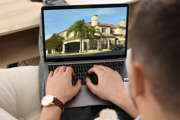 Man looking for house on real estate market website at home, closeup