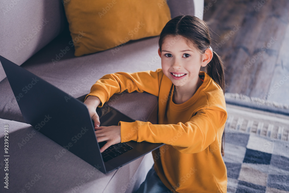 Canvas Prints Photo portrait of cute small girl sit couch netbook browsing dressed orange outfit cozy day light home interior living room