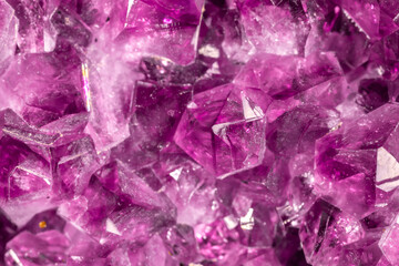 Fototapeta premium Amethyst purple crystals. Gems. Mineral crystals in the natural environment. Texture of precious and semiprecious stones. Seamless background with copy space colored shiny surface of precious stones.