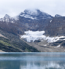 A mountain with a snow covered peak and a lake below