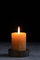 Burning candle in wooden holder on grey table, space for text.