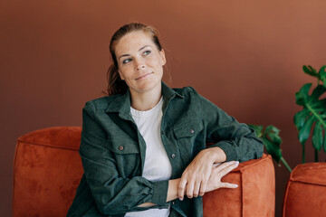 A cunning woman, thinking about an idea, sits on the sofa.