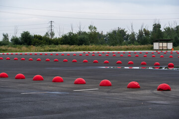 Empty parking lot with red traffic cones in rural area in summer.