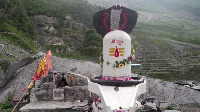 White sculpture of Shiva Lingam with the serpent god Shesh Naag on top, symbolizing Deity Shiva, in the valley of Chamba Kailash during the Mani Mahesh Yatra, a Hindu pilgrimage.