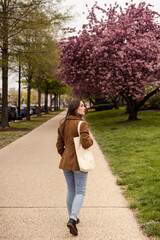 Young woman walking away carrying a tote bag.