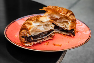 Pain au chocolat or chocolate croissant torn in half on a plate on the table