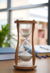 An hourglass with a blurred background of a modern office - Symbolizing pressure and the strain of deadlines
