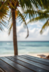 Fototapeta premium Top of wood table with seascape and palm tree, blur bokeh light of calm sea and sky at tropical beach background