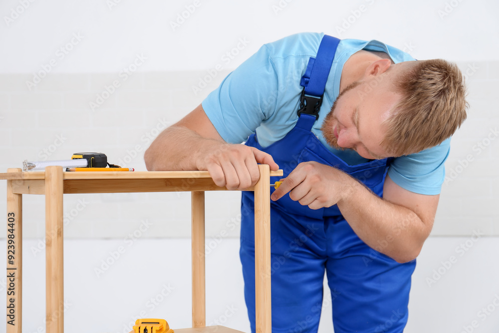 Wall mural Worker with screwdriver assembling wooden furniture indoors