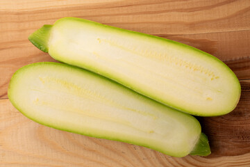 Two halves of ripe zucchini on a wooden table, macro, top view.