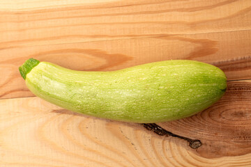 One ripe zucchini on a wooden table, macro, top view.