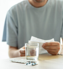 a man reads the instructions for use of medicines, medical prescription, blisters with pills on the...