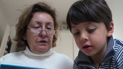 Grandmother with glasses reading a book to her attentive grandson. focused expressions and the engaging storytelling session, emphasizing the importance of family bonds and shared learning