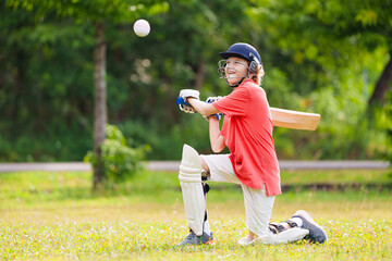 Kids playing cricket in summer park