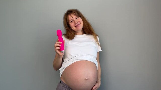 Happy pregnant young woman with sex toy for adults, female with vibrator 
