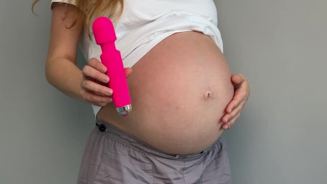 Happy pregnant young woman with sex toy for adults, female with vibrator 