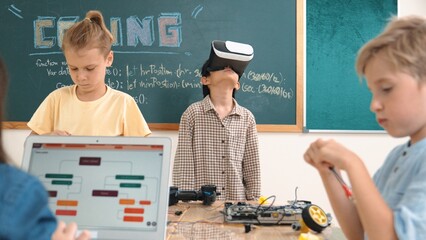 Energetic child wearing Vr headset while enter virtual world at classroom. Student programing...