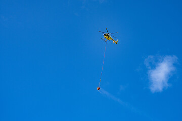 Fire helicopters fetch water from the sea to put out wildfires on the mountain. Mālaekahana State Recreation Area, Laie Bay, Oahu, Hawaii. Hukilau Beach Park

