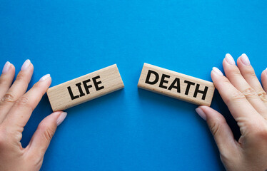 Life or Death symbol. Concept word Life or Death on wooden blocks. Businessman hand. Beautiful blue background. Business and Life or Death concept. Copy space